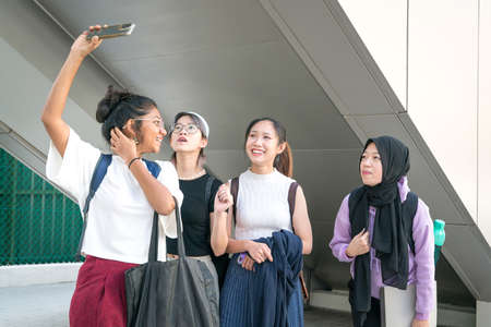 Group of young college multi-racial women students having fun, laughing and taking selfie together.の写真素材