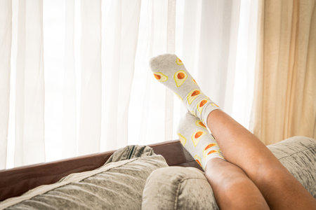 Young woman lying on the bed with raised legs up, against the windows. Copy space.の写真素材