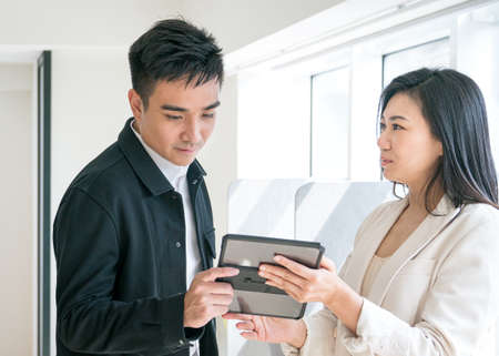 Business colleagues having a discussion while looking at digital tablet. Office or workplace...