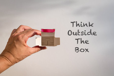 Word, Think outside the box next to fingers holding an open small box.