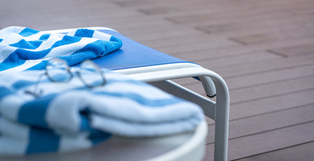 Pool towel on lounge chair with eyeglasses and pool background. Summer vacation concept.