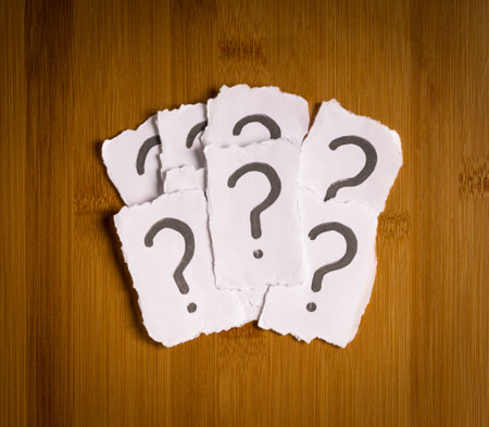 Heap of white papers with question mark. Top view. Confusion or indecision concept.の写真素材