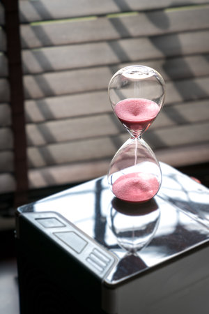 Sand running or flowing down of an hourglass measuring the passing of time. Close up view, copy space.の写真素材