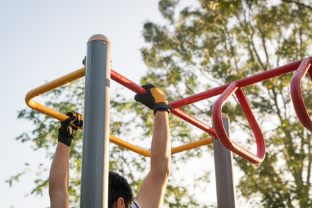 Man working out outdoors, arms swinging on monkey bar. Strength training or fitness exercise concept.の写真素材