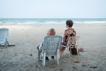 Senior couple relaxing on the beach, watching the sea. Holiday and vacation concept for the elderly and retirees.の写真素材