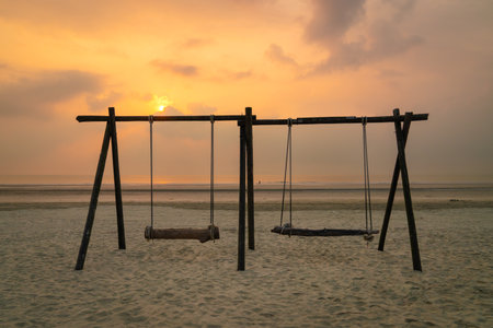 Beach landscape with swing set during sunrise. Travel vacation concept.の写真素材