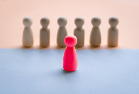 A red wooden doll facing a row of dolls separated by different floor colors. Leadership concept.