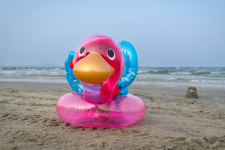 Inflatable duck on a sandy beach. Sea and blue sky at the background. Summer vacation and holiday concept.の写真素材