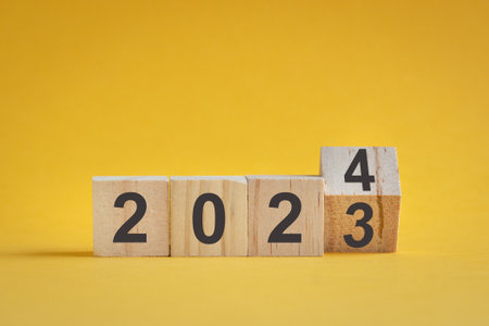 Wooden cube stock flipping, change from 2022 to 2023. Yellow color background, with copy space.