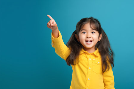 Asian female child posing with hand gesture. On blue background, copy space.の素材