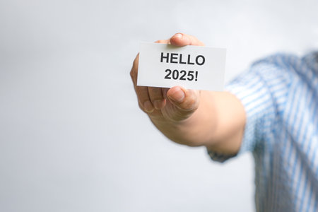 Man holding a white card with Hello 2025. On white background, copy space.の写真素材