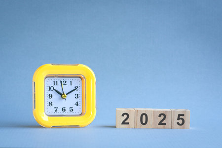 2025 on wood block, next to clock. New year concept.の写真素材