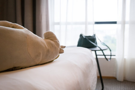 Hotel room with soft toy on top of bed and woman's handbag on top of coffee table.の写真素材