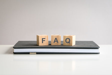Text FAQ on wooden blocks on top of a notepad of a white color table.の写真素材