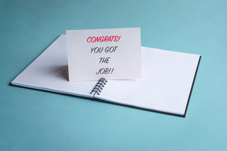 Congrats you got the job, a message on a white card on top of a notepad. New job or employment...