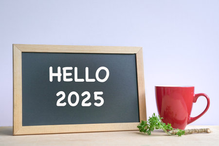 Hello 2025, text on a blackboard next to coffee in red cup. New year.