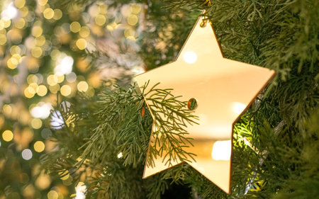 Christmas decoration of a golden star hanging on tree with bokeh light background.の写真素材