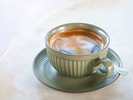 Hot black coffee in green cup and saucer on white marble table.の写真素材