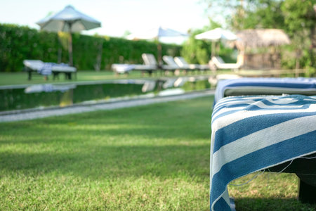 Deckchairs covered with towel, blur pool background. Holiday or vacation concept.の写真素材