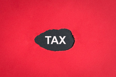 Tax on a ripped torn red paper with black background. Copy space.の写真素材