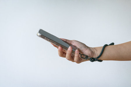 Woman holding a phone with a wrist strap. Close up view. Isolated on white background.