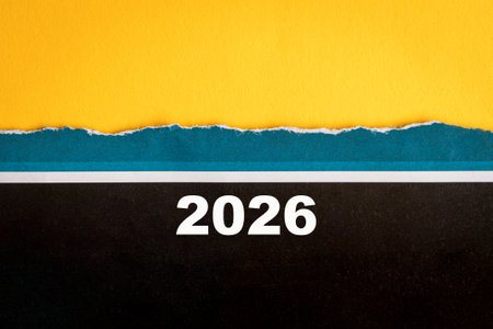 2026 on torn black and blue paper, on top of yellow surface. Copy space.