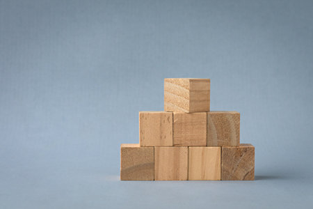 Wooden square blocks arranged in pyramid shape. Isolated on light background, copy space.の写真素材