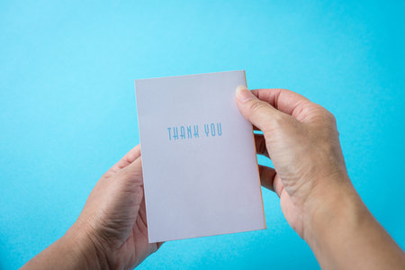 Holding a thank you card. Against the light blue background.の写真素材