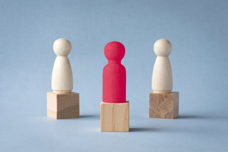 Red figurine wood block on top of podium. Stand out among other figurines. Leadership or champion concept.の写真素材