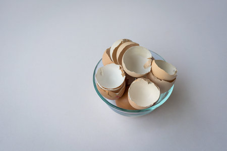 Broken chicken egg shells in a bowl isolated on white background.