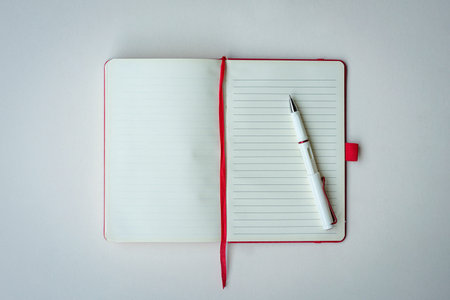 Open lined notebook with red bookmark and pen. Isolated on white surface, top view. Copy space.の写真素材