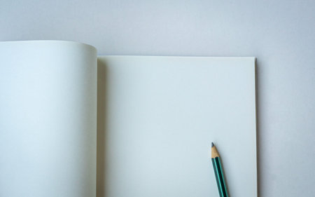 Pencil on top of an open blank notepad. Isolated on white surface. Space for text.の写真素材