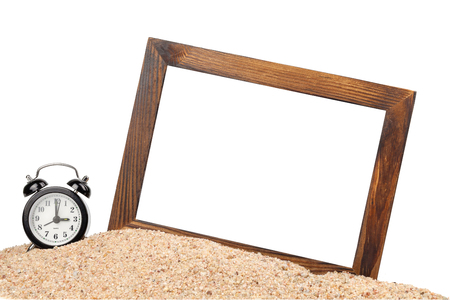 wooden picture frame and alarm clock on the beachの写真素材