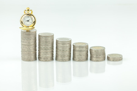 stacks of coins and  pocket watch on white a backgroundの写真素材