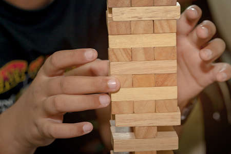 The tower from wooden blocks and man's hand take one blockの写真素材