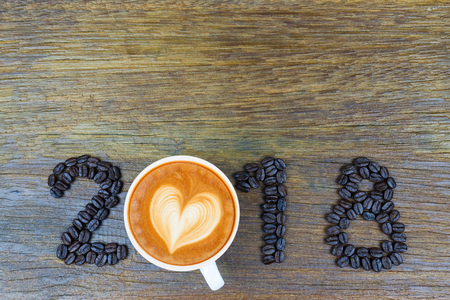 2018 coffee beans and a cup of coffee on wood for new year concept background