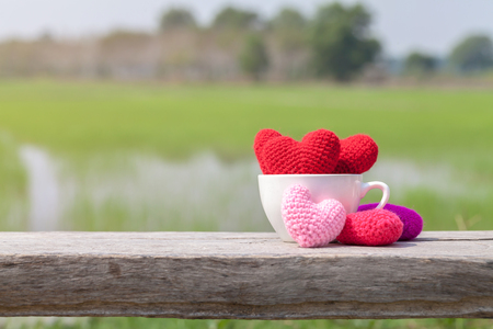 Red hearts in white ceramic cup on wood with nature backgroundの写真素材