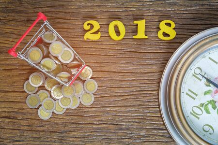 2018 New year and saving concept with shopping cart or supermarket trolley, on wood background,...