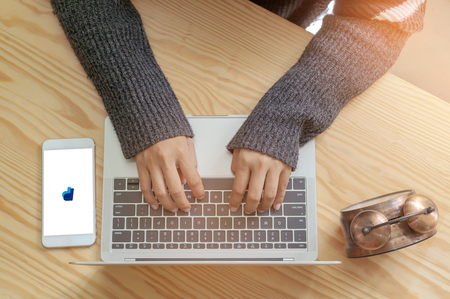 Rayong, THAILAND, June 20, 2019 : Hands on the keyboard close up. View from above. Woman is working at the computer. Near the mobile phone on the screen is a symbol of Paypal.のeditorial素材