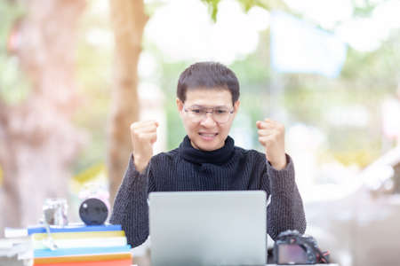 Excited worker sitting at desk in working space use computer reading message looking at device screen received great unbelievable opportunity or reward. Motivated employee celebrating job promotionの写真素材