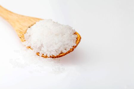 Salt or sugar on a wooden teaspoon on white background, isolatedの写真素材