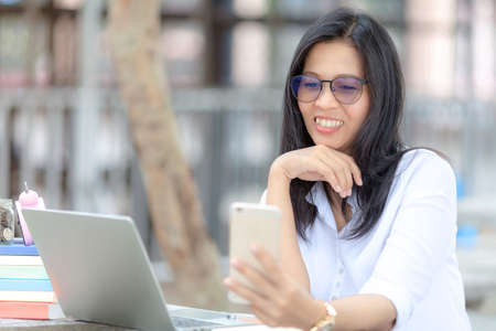 business woman in glasses works with a smartphone in a cozy park