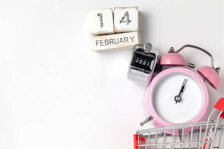 alarm clock in a pink plastic case and black hands in a metal shopping cart with tally click counter  on a white background selective focus isolatedの写真素材