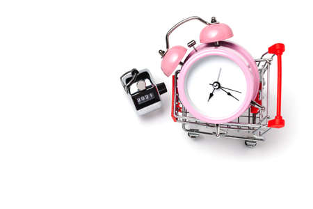 alarm clock in a pink plastic case and black hands in a metal shopping cart with tally click counter  on a white background selective focus isolatedの写真素材