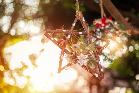 New Year and Christmas toy in a shape of brown star hanging on a Christmas tree surrounded by other toys and lights.の写真素材