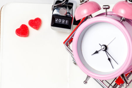 Alarm clock, red jelly heart on a white background. Good morning or working space. Flat-lay, top view.の写真素材