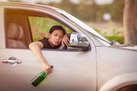 dangerous driving - young woman drinking beer and driving car,  drinking alcohol in vehicle and road...