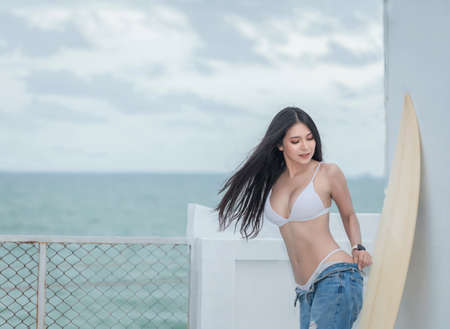 Young pretty fit sporty woman  with white bikini outside resort enjoying vacation. Tropical sea view...
