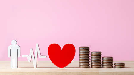 Red heart near coin stacks over the pink background. copy space. money coins stairs to love and...
