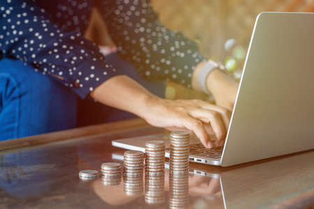 Businesswoman hand working with coin money currency. Concept of investment growth and money saving in morning light. selective focus.の写真素材